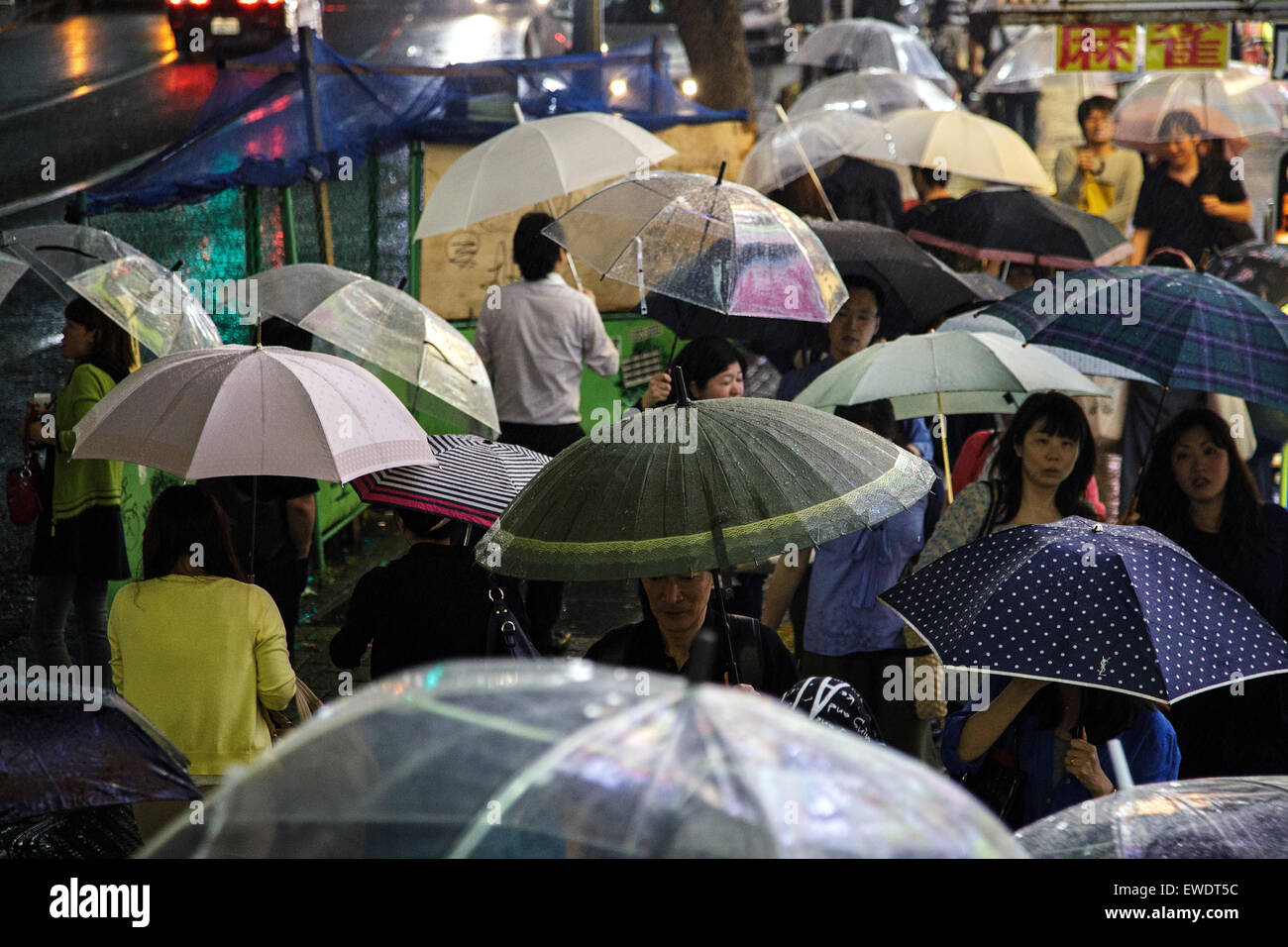 Menschen mit Regenschirmen im Regen in Shibuya in der Nacht in Tokio, Japan Stockfoto