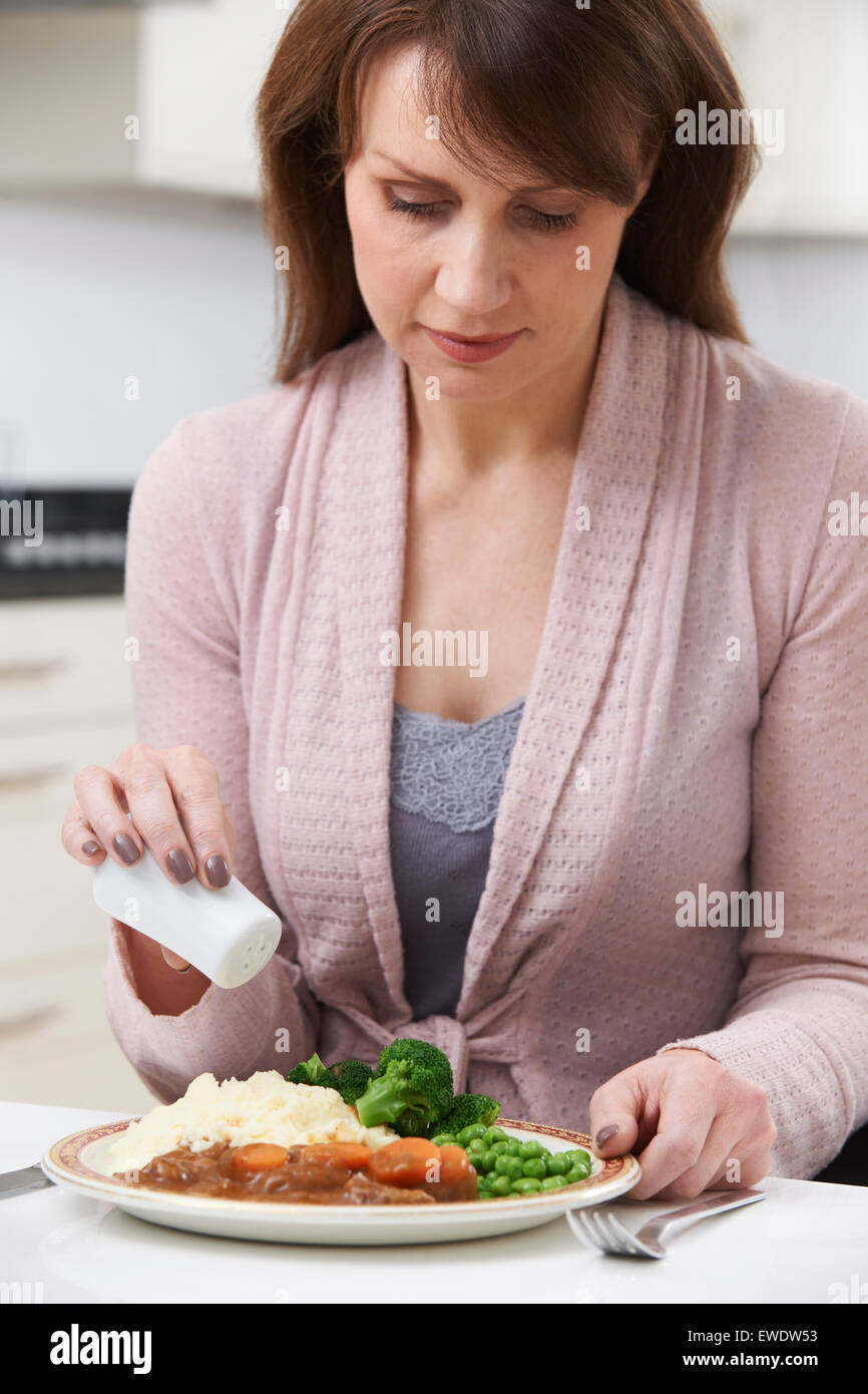 Frau im Hause hinzufügen von Salz zu essen Stockfoto