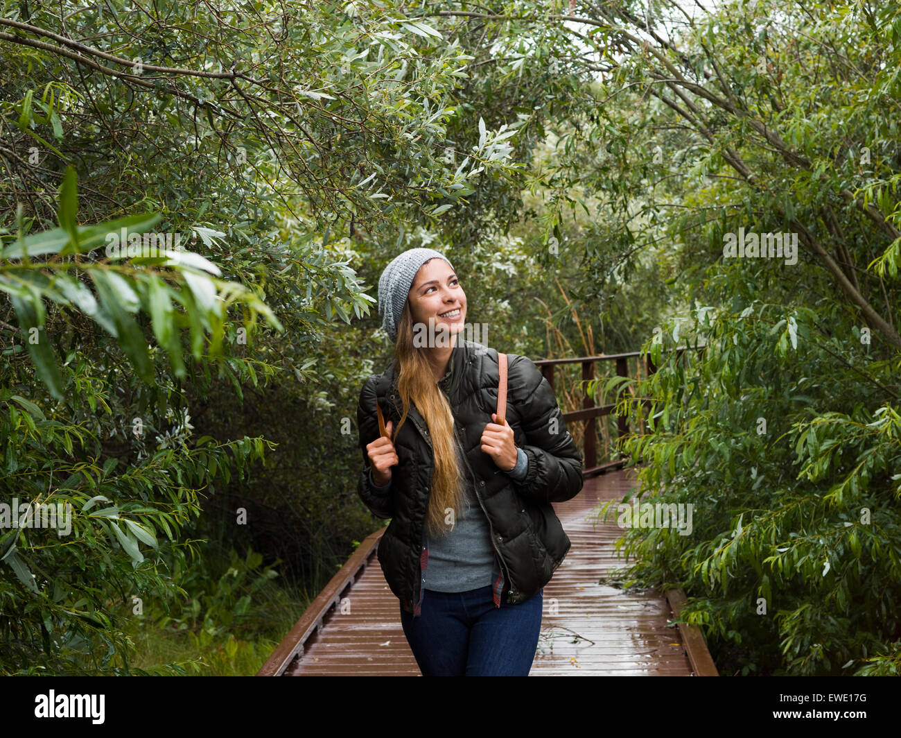 Lächelnde junge Frau zu Fuß durch den Wald in einem park Stockfoto
