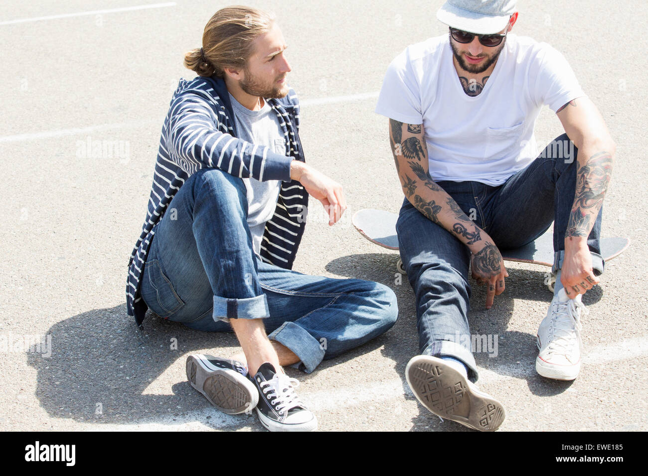 Zwei junge Männer sitzen auf dem Boden, im Chat Stockfoto