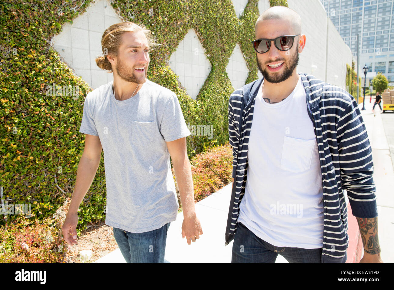 Zwei junge Männer zu Fuß entlang ein Fußweg Straßenleben Jugend lächelnd Stockfoto