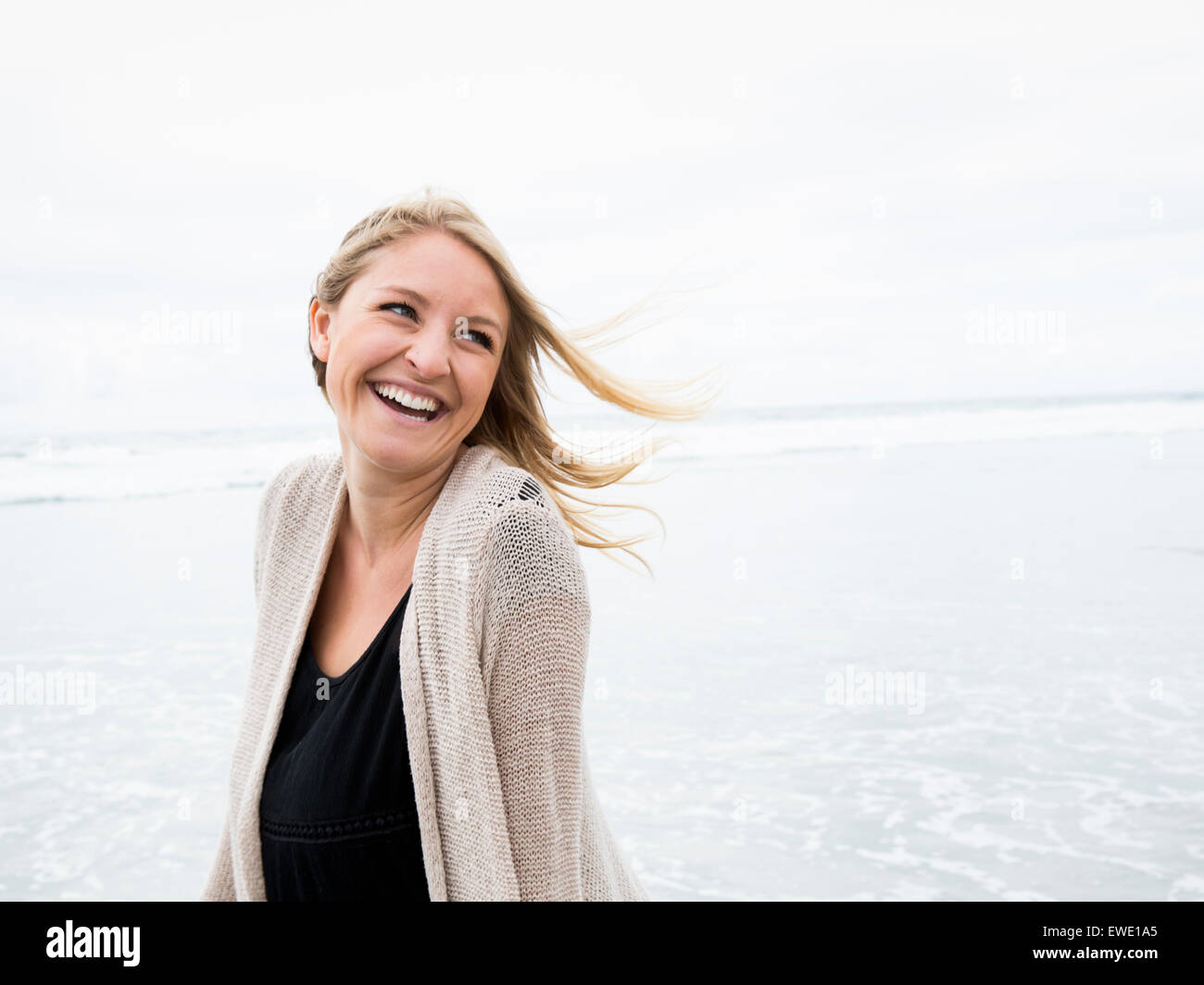 Porträt einer lächelnden jungen Frau am Strand Stockfoto
