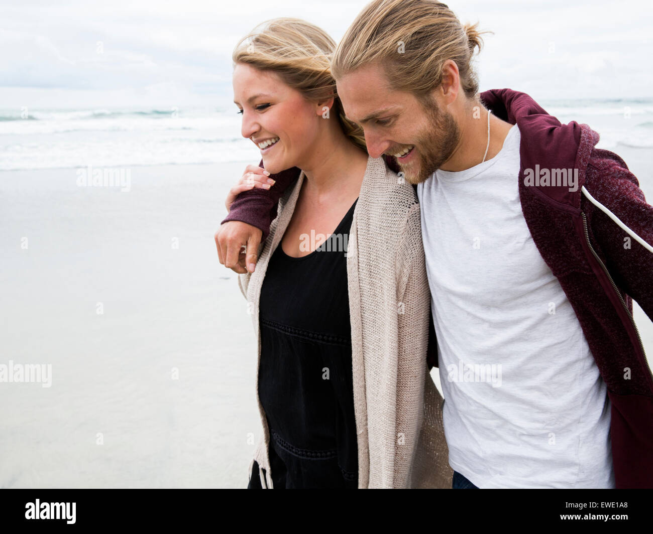Junger Mann und junge Frau, die zu Fuß am Strand, Lächeln Stockfoto