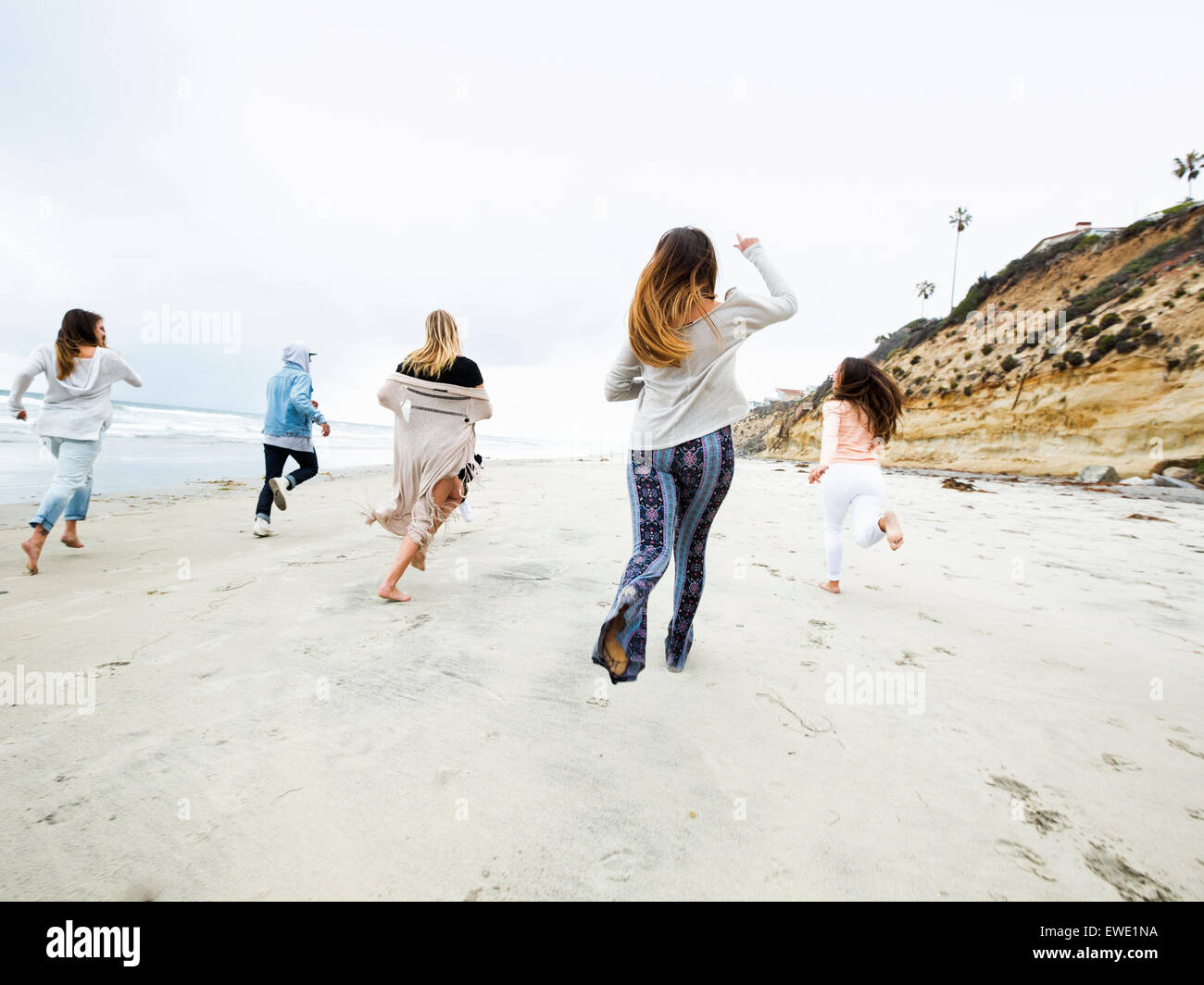 Eine Gruppe junger Männer und Frauen laufen am Strand, Spaß Stockfoto