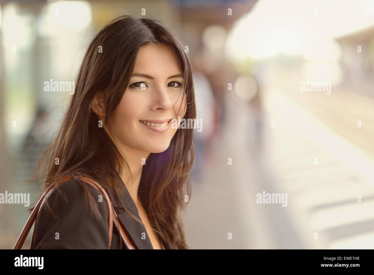 Lächelnde Brünette Frau stehend in einem Bahnhof am Morgen pendeln zur Arbeit in einer Öko-freundliche Art und Weise Stockfoto