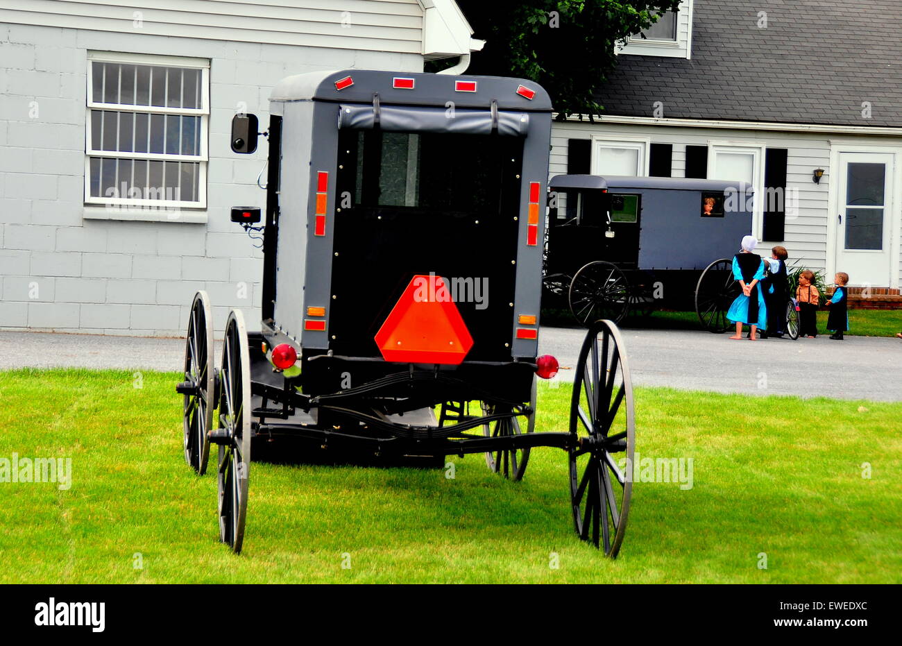 Lancaster County, Pennsylvania: A geparkt Amish Buggy sitzt auf der Gras- und Amish Kinder spielen um eine zweite * Stockfoto