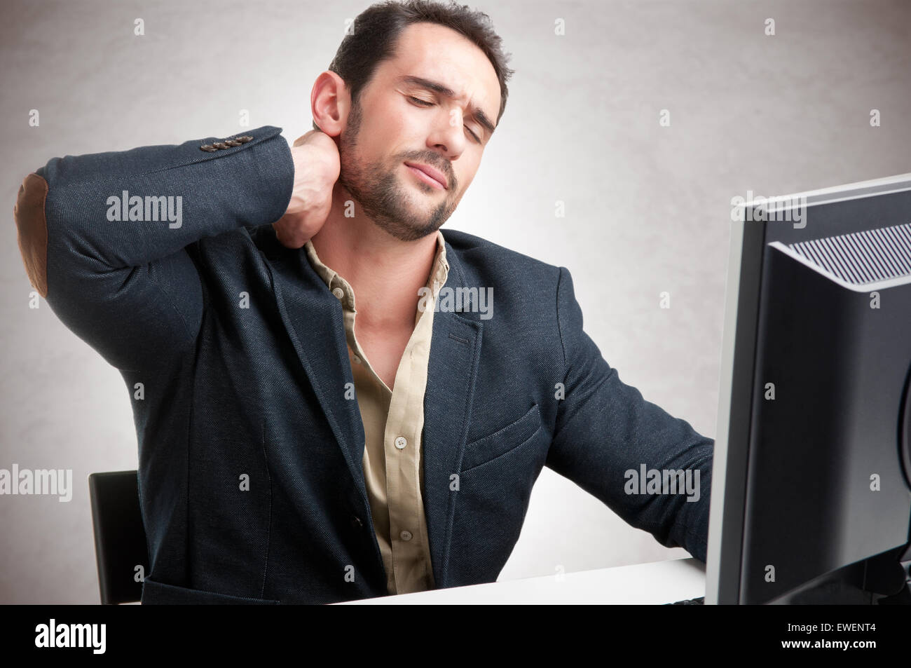 Lässige Geschäftsmann in einem Schreibtisch mit Schmerzen im Nacken sitzen Stockfoto