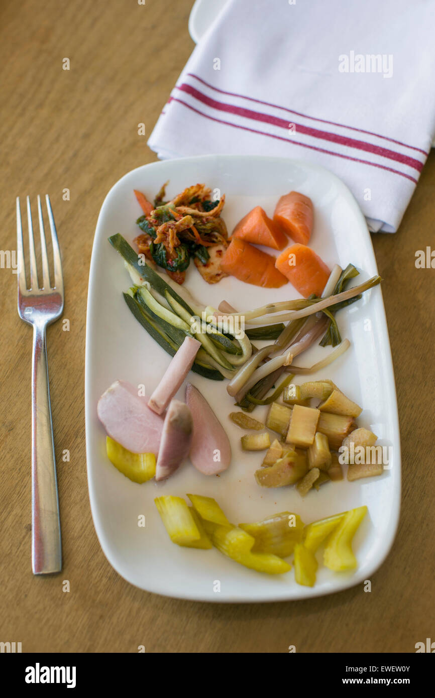 Teller mit eingelegtem Gemüse, einschließlich Kimchi, Rüben, Karotten, Sellerie Kurkuma, Rhubard und Rampen und Gabel und Tuch Serviette Stockfoto