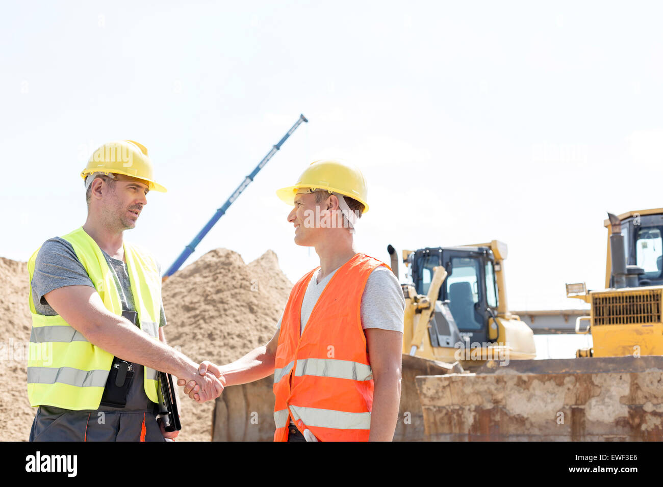 Architekten, Händeschütteln auf Baustelle gegen klaren Himmel Stockfoto