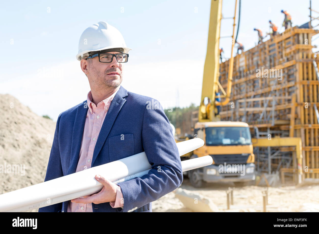 Zuversichtlich Architekten halten aufgerollt Blaupausen auf Baustelle Stockfoto