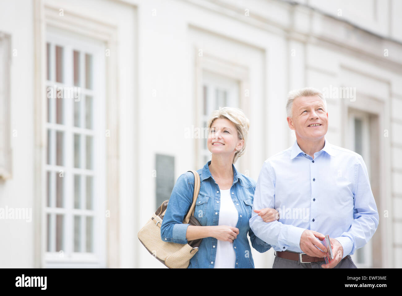 Glückliches Ehepaar mittleren Alters stehend mit Arm in Arm vor Gebäude Stockfoto