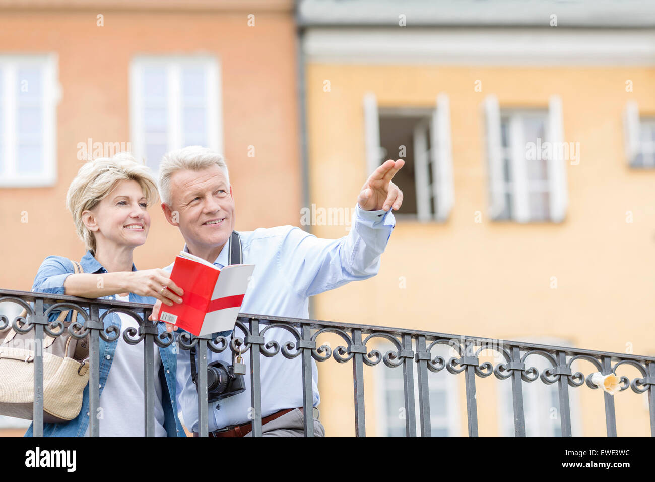 Glücklicher Mann zeigen etwas auf eine Frau mit Reiseführer in Stadt Stockfoto