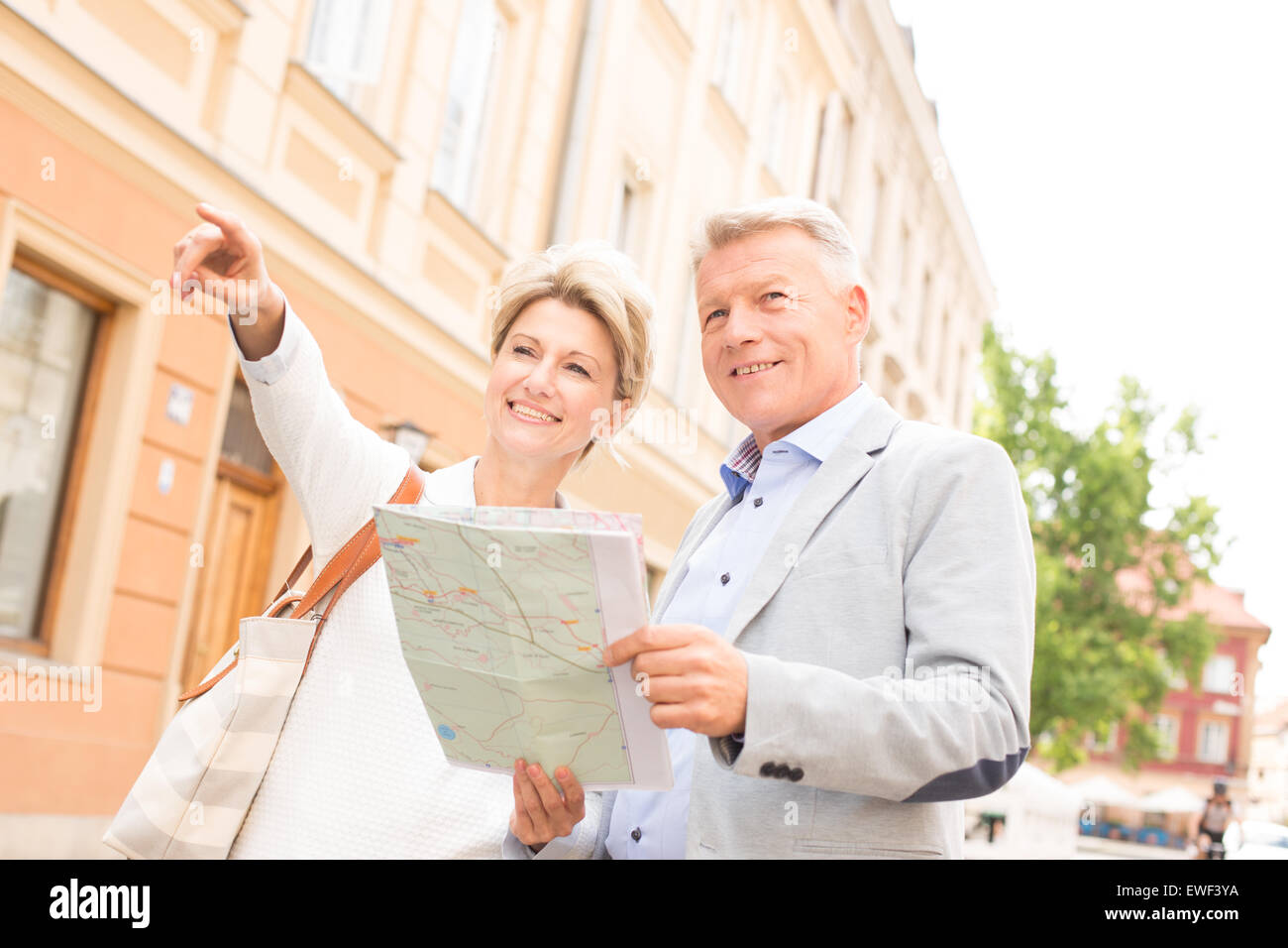 Frau mittleren Alters zeigen etwas man mit Straßenkarte in Stadt Stockfoto