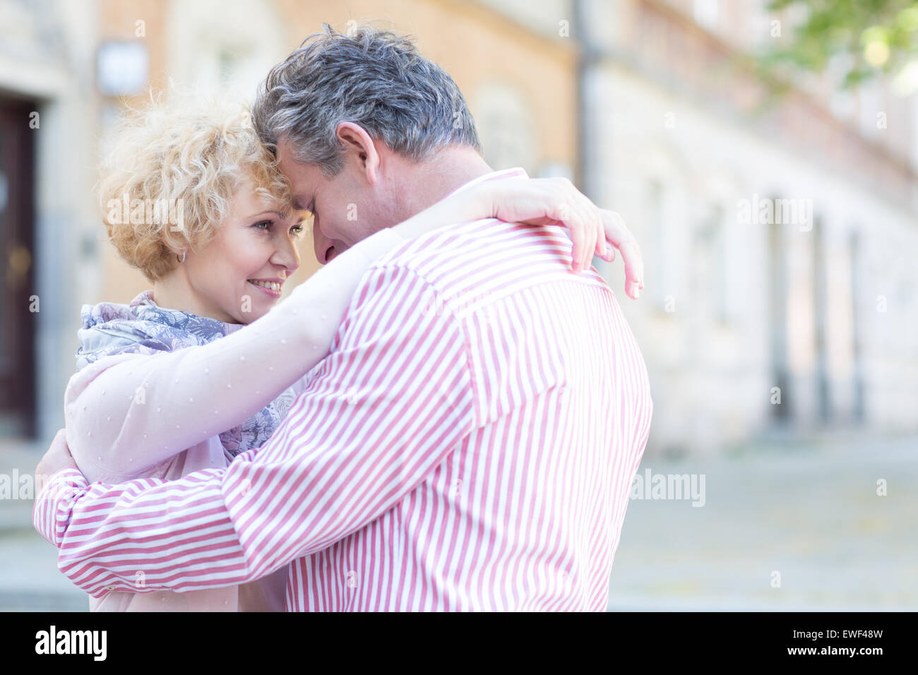 Glückliches Ehepaar mittleren Alters in Stadt umarmen Stockfoto