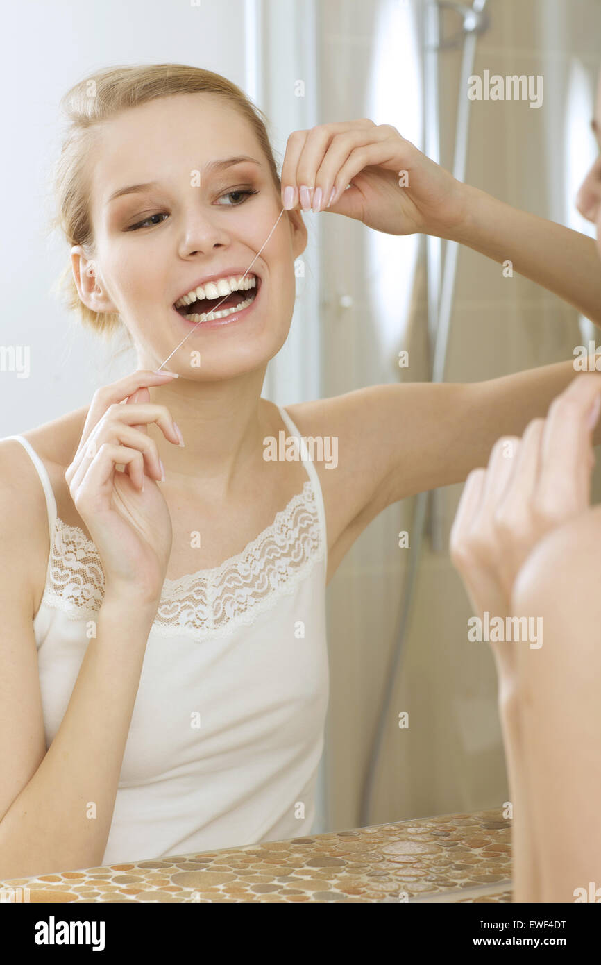 Eine junge Frau, die ihre Zähne Zahnseide Stockfoto
