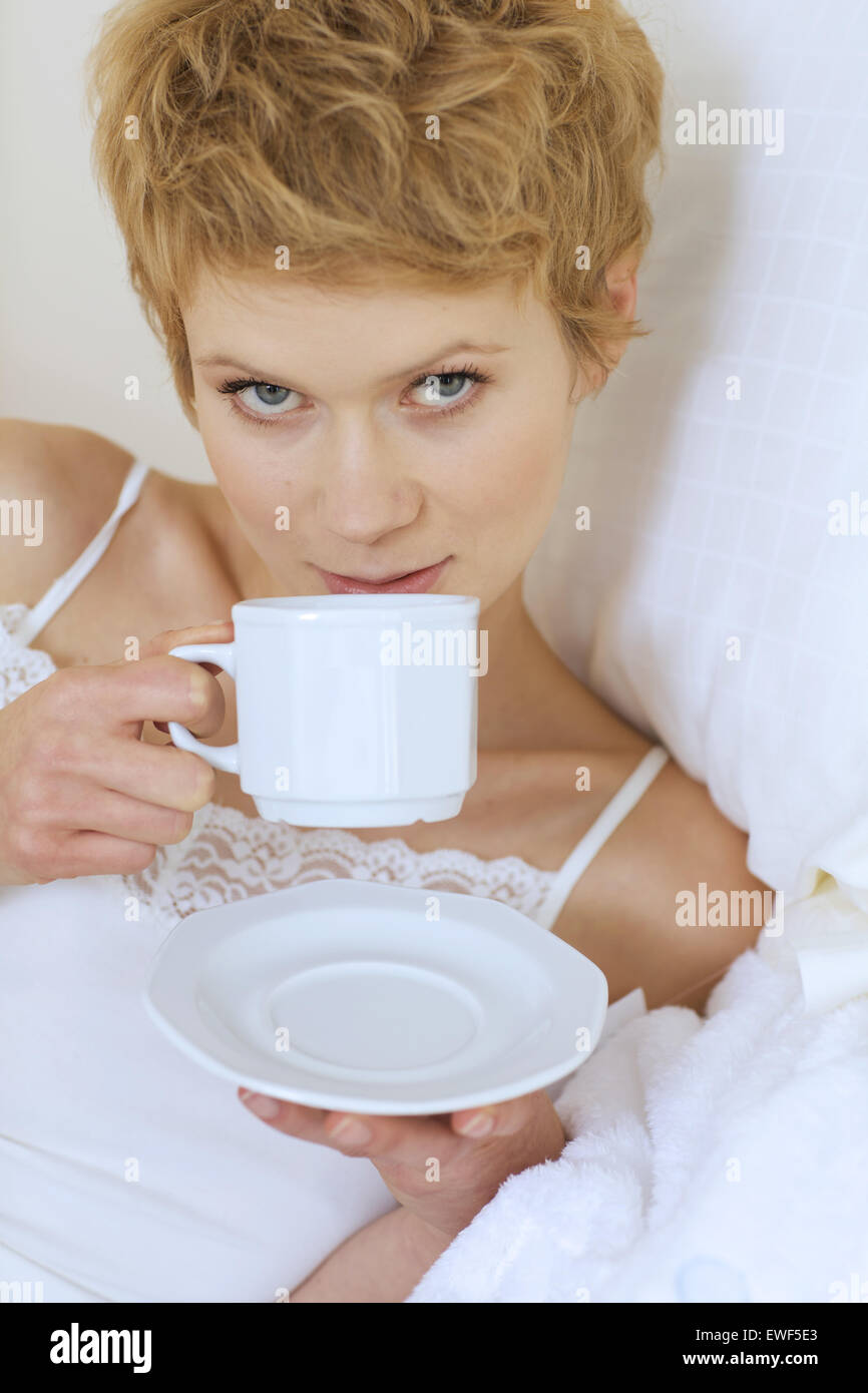 Frau trinkt Kaffee im Bett Stockfoto