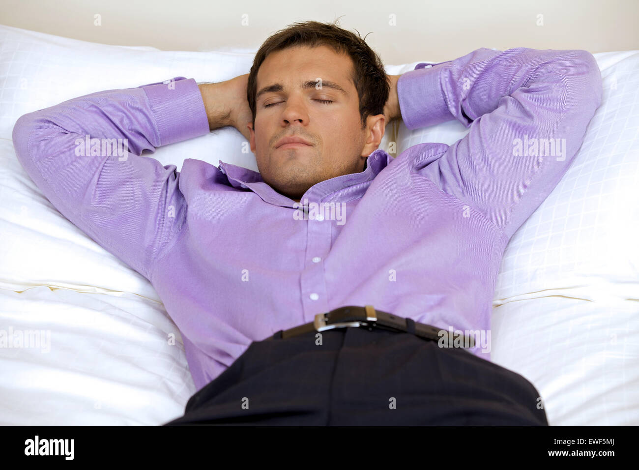 Entspannende Mann im Hotelzimmer mit Händen hinter dem Kopf, Augen geschlossen Stockfoto