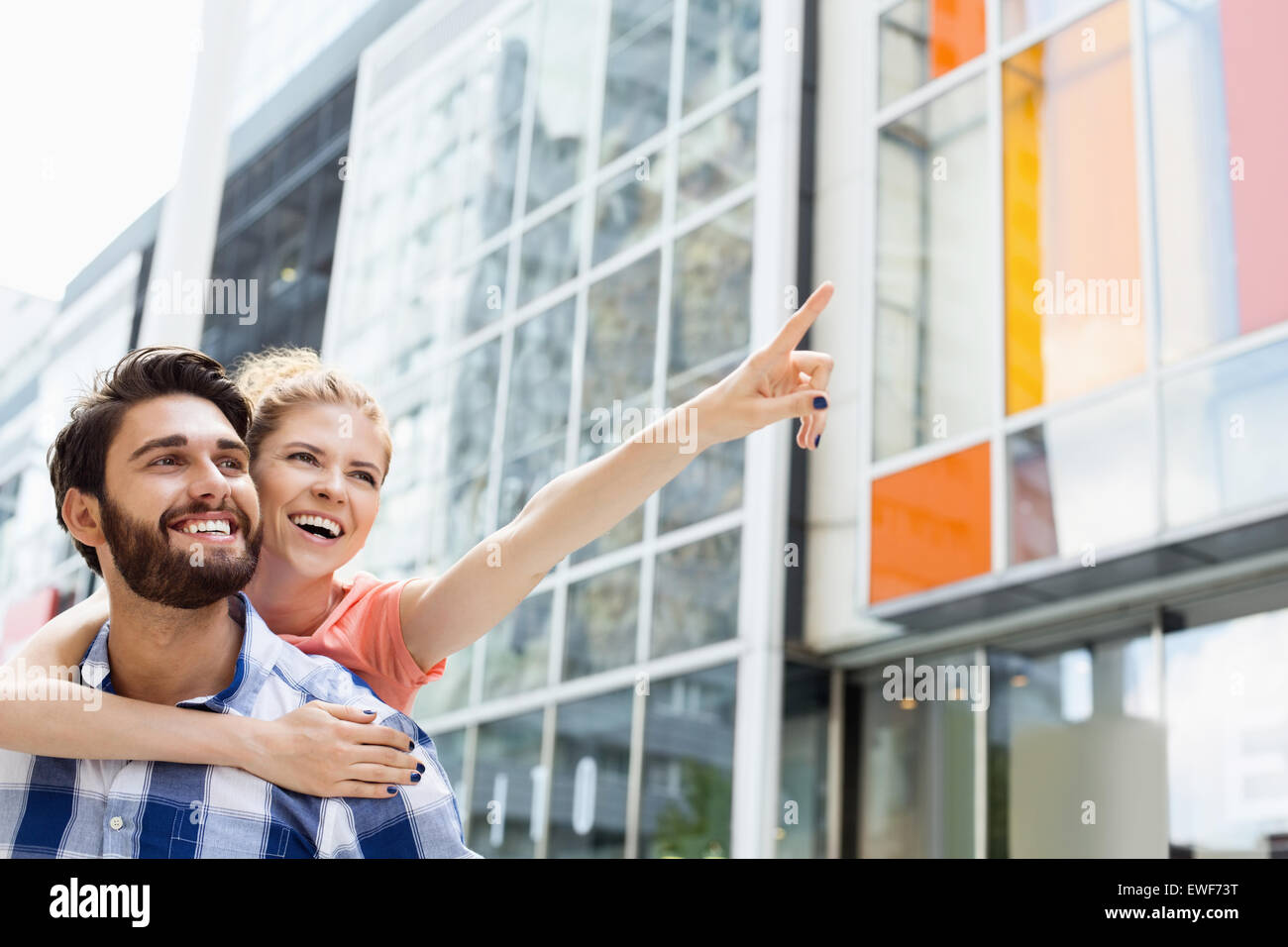 Fröhliche Frau, die etwas zeigen Menschen und genießen Sie Huckepack Fahrt in die Stadt Stockfoto