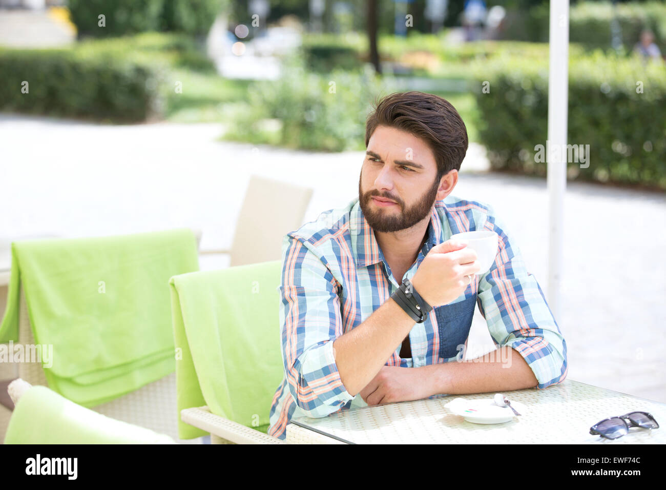 Nachdenklicher Mann halten Kaffeetasse im Straßencafé Stockfoto