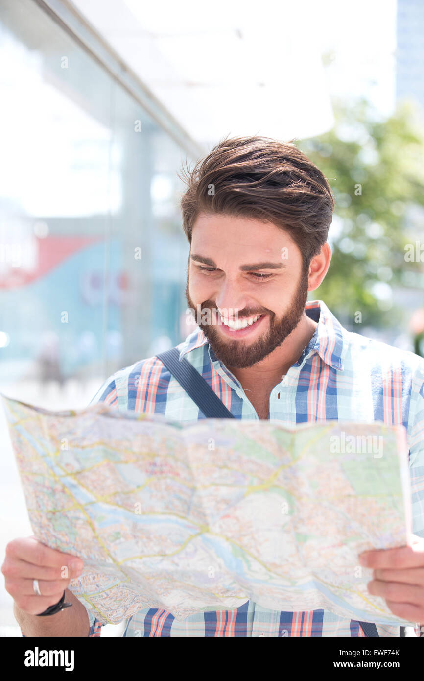 Glücklicher Mensch lesen Straßenkarte in Stadt Stockfoto