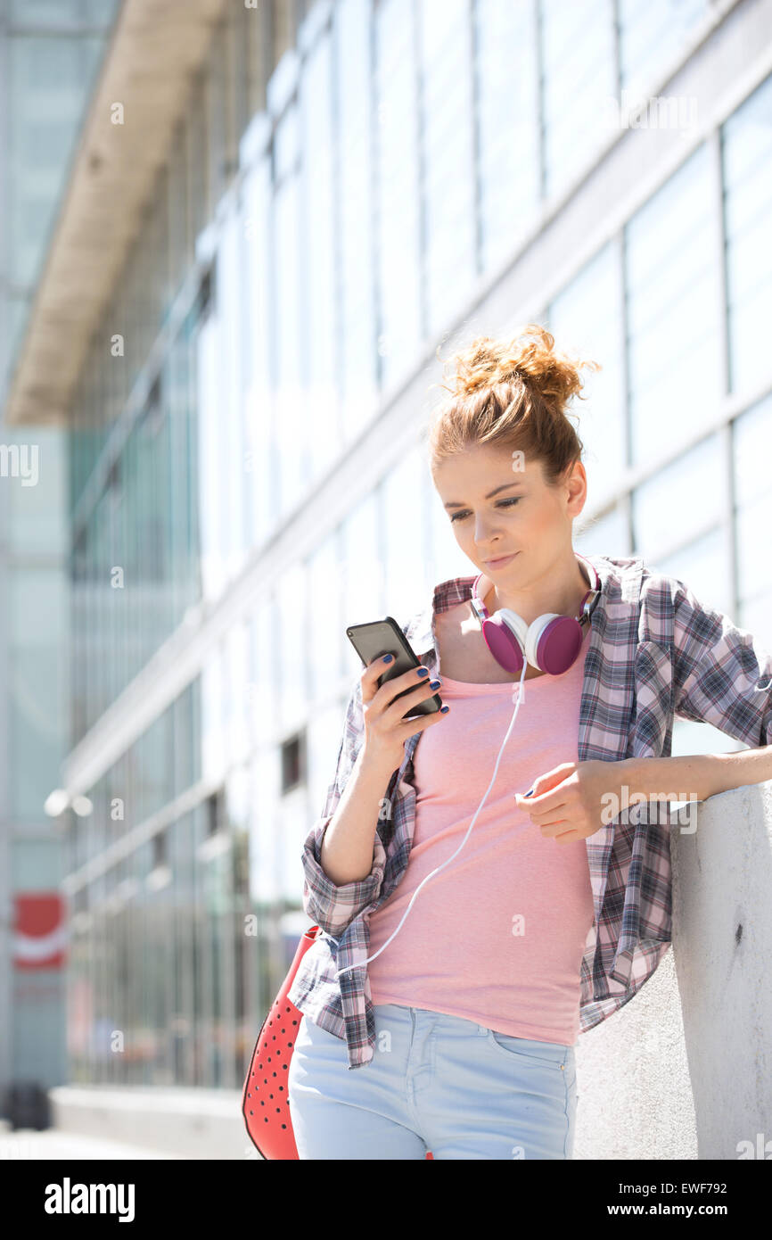 Junge Frau mit Smartphone vor Bürogebäude Stockfoto