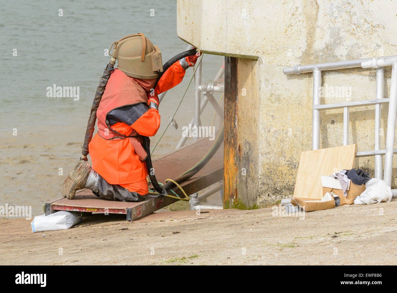 Sandstrahlen. Ein Arbeiter tragen von Schutzkleidung beim Sandstrahlen kniete. Stockfoto