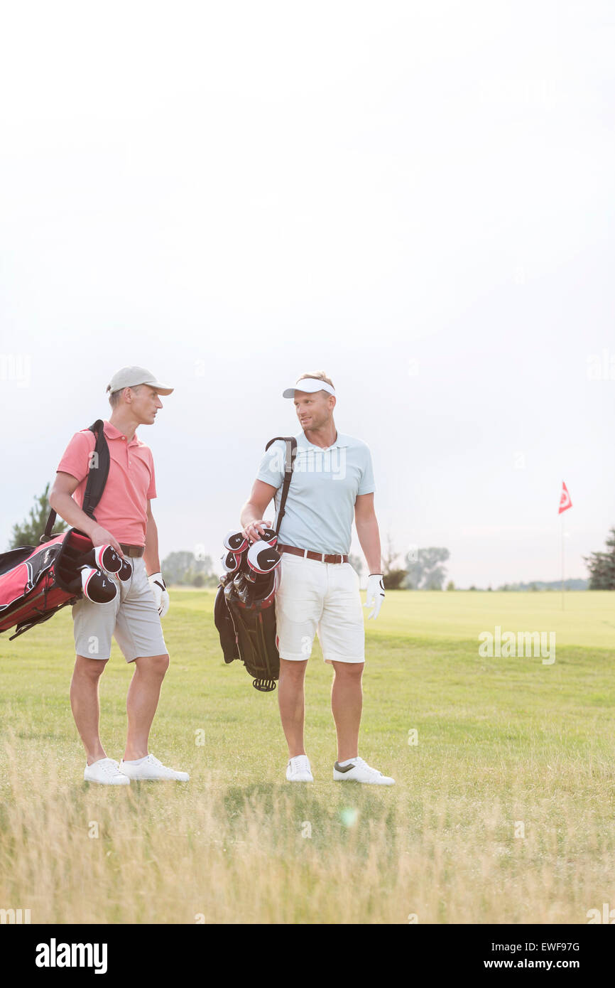 Männer im Gespräch am Golfplatz gegen klaren Himmel in voller Länge Stockfoto