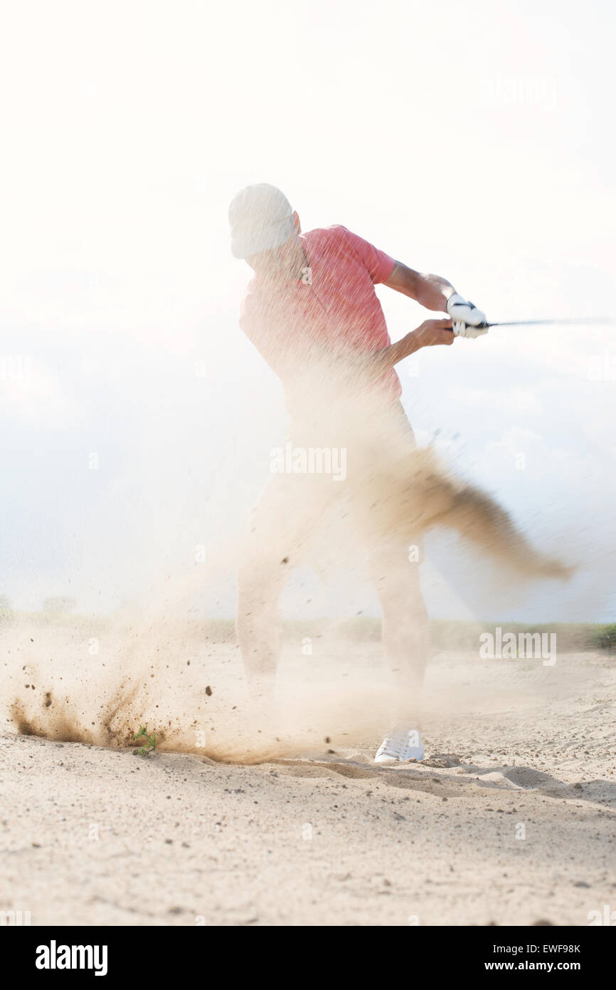 Mann mittleren Alters plantschen Sand während des Spielens auf Golfplatz Stockfoto