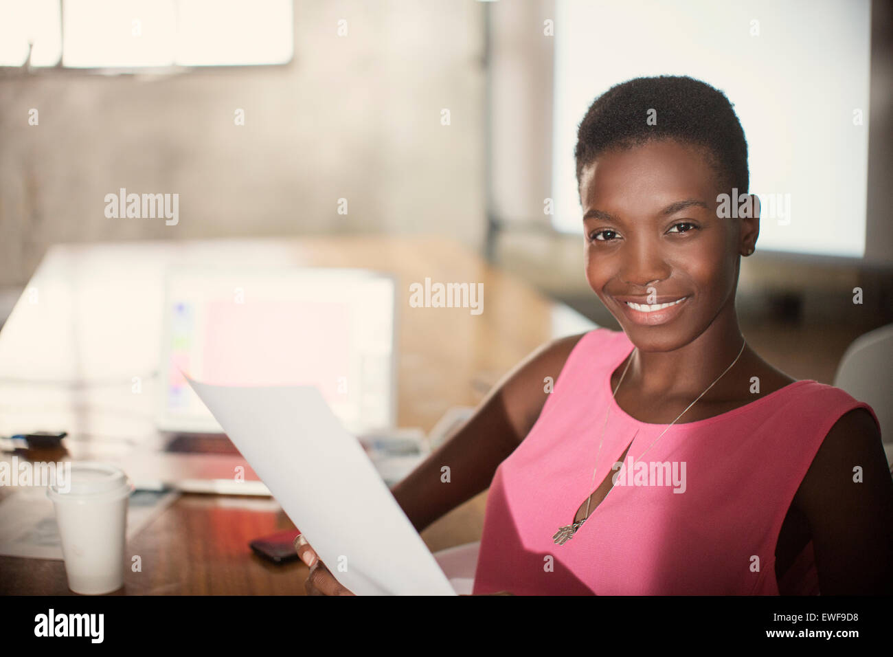 Porträt lächelnd Geschäftsfrau mit Papierkram im Büro Stockfoto