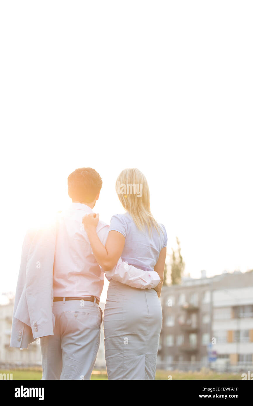 Rückansicht des Geschäfts paar stehend mit Waffen um gegen den klaren Himmel an sonnigen Tag Stockfoto