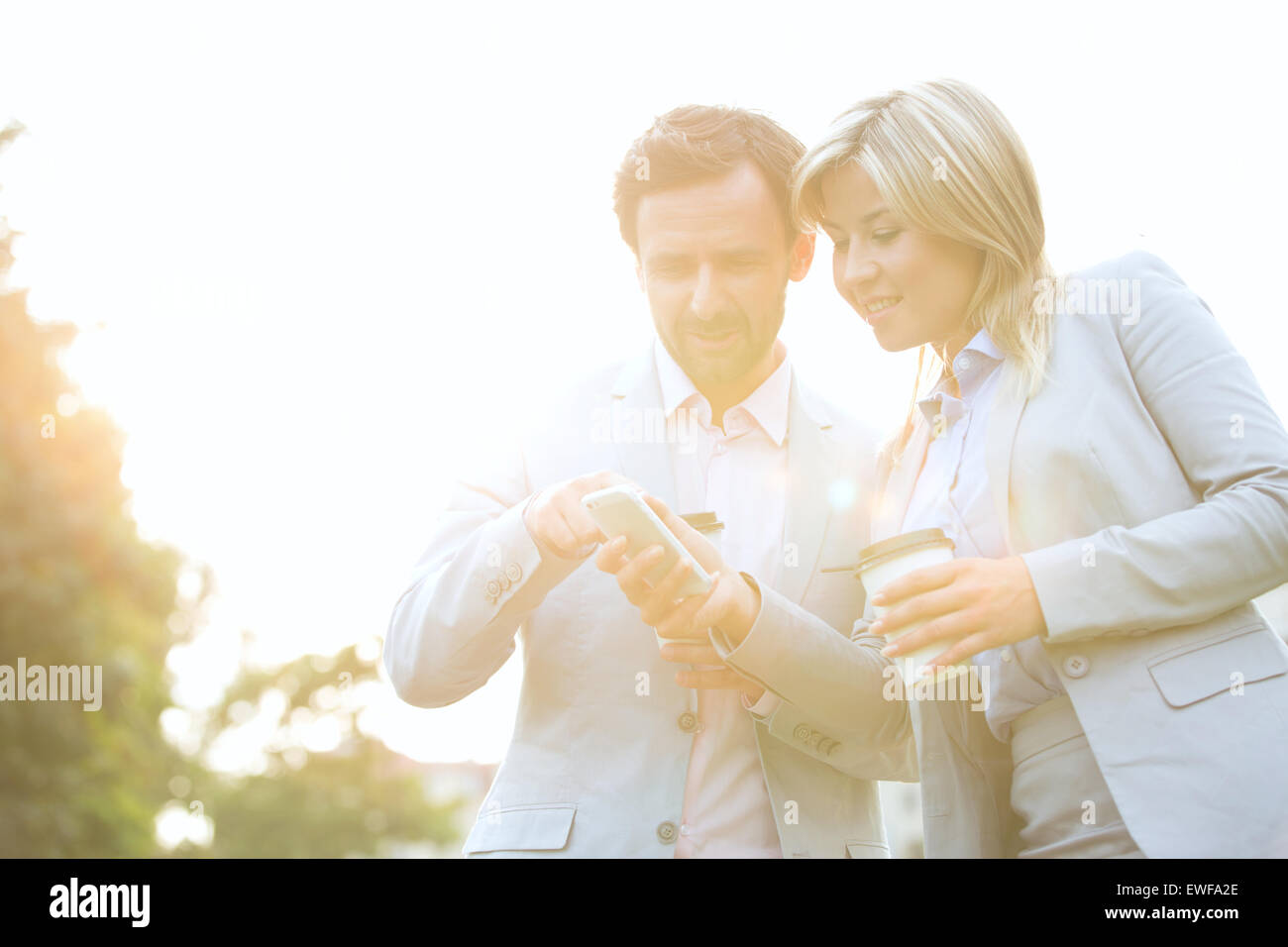 Business-paar im Gespräch bei der Verwendung von Handy auf sonnigen Tag Stockfoto