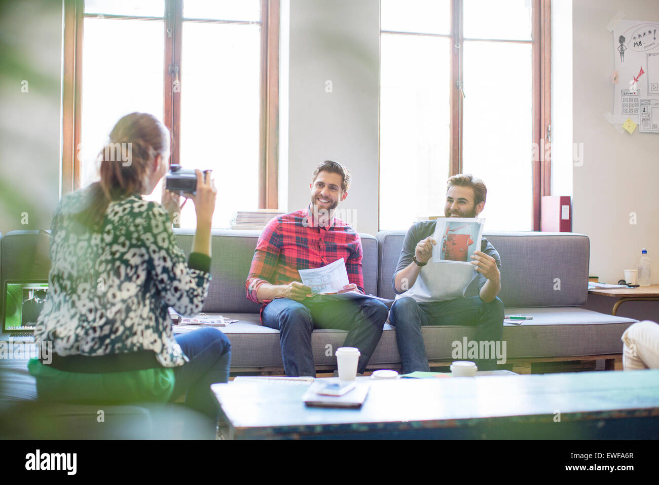 Kreative Geschäftsmann posiert mit Foto für Mitarbeiter mit Sofortbild-Kamera im Büro Stockfoto