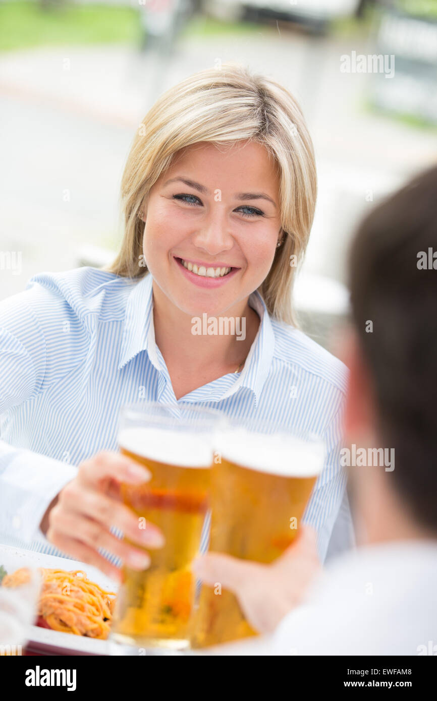 Schöne Geschäftsfrau Toasten Bierglas mit männlichen Kollegen im restaurant Stockfoto