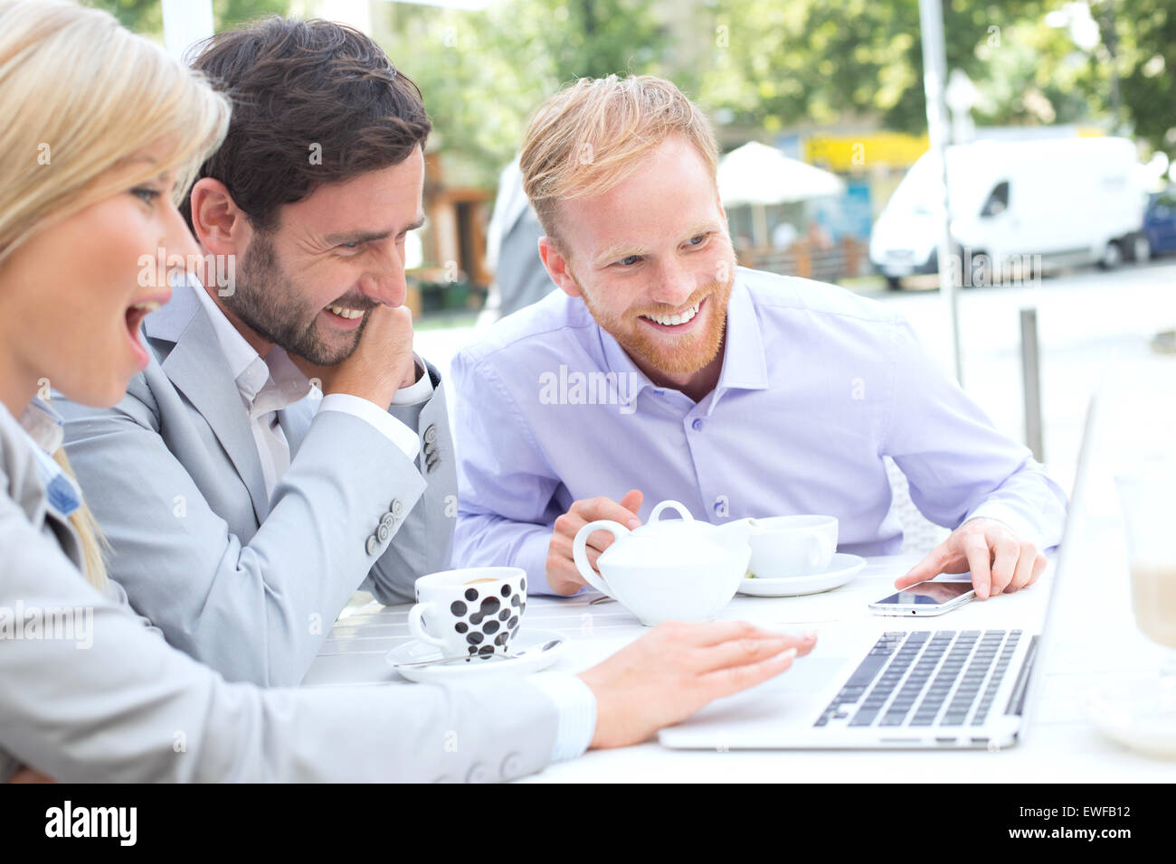 Fröhliche Geschäftsleute Laptop zusammen mit Straßencafé Stockfoto