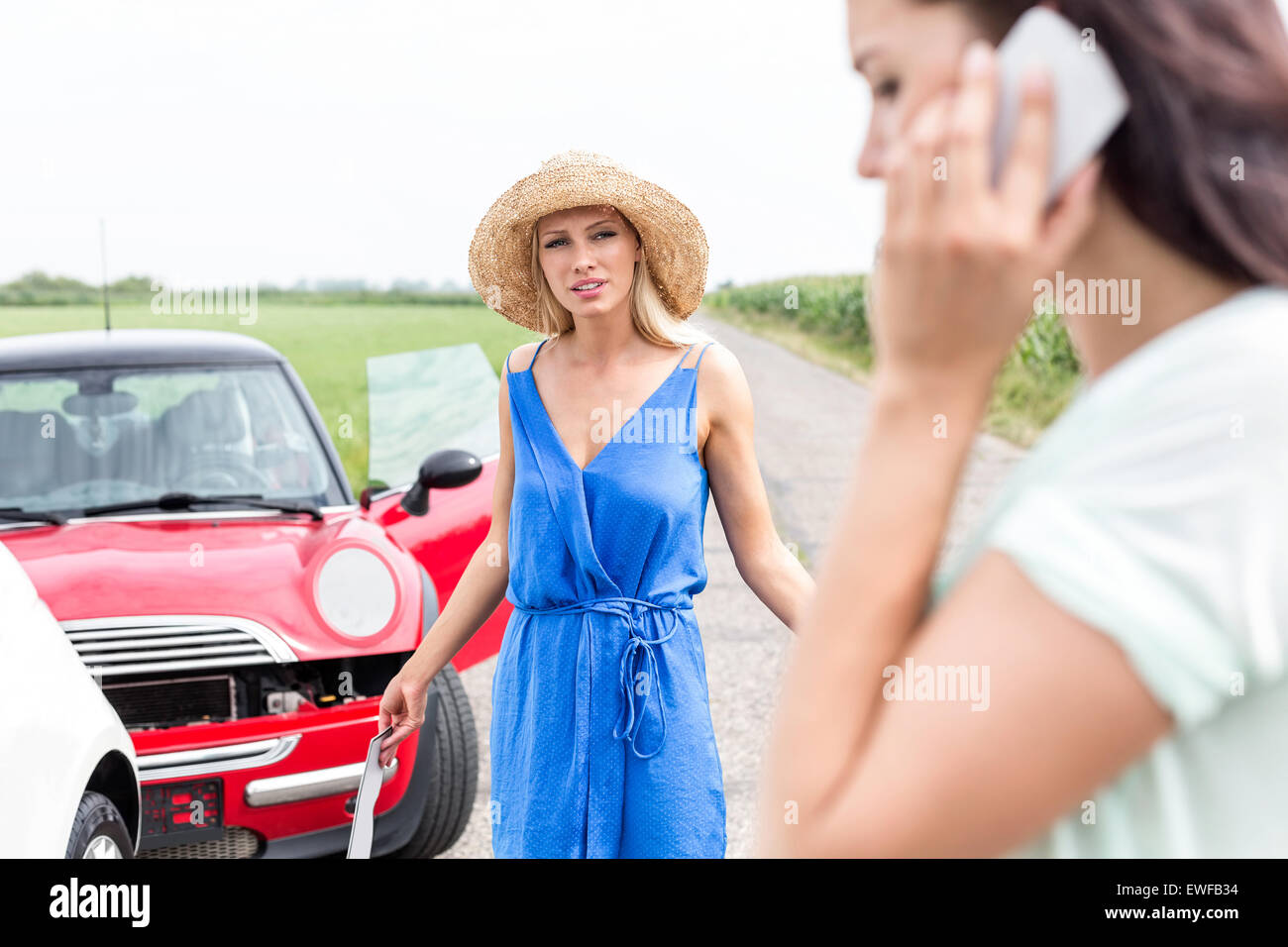 Böse Frau weiblich mit Handy von beschädigten Autos unterwegs betrachten Stockfoto