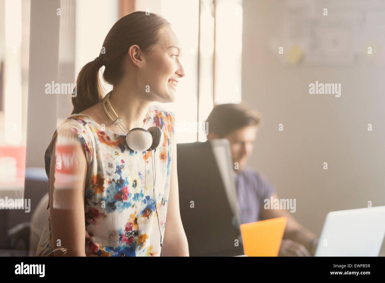 Lächelnde Geschäftsfrau mit Kopfhörer im Büro Stockfoto