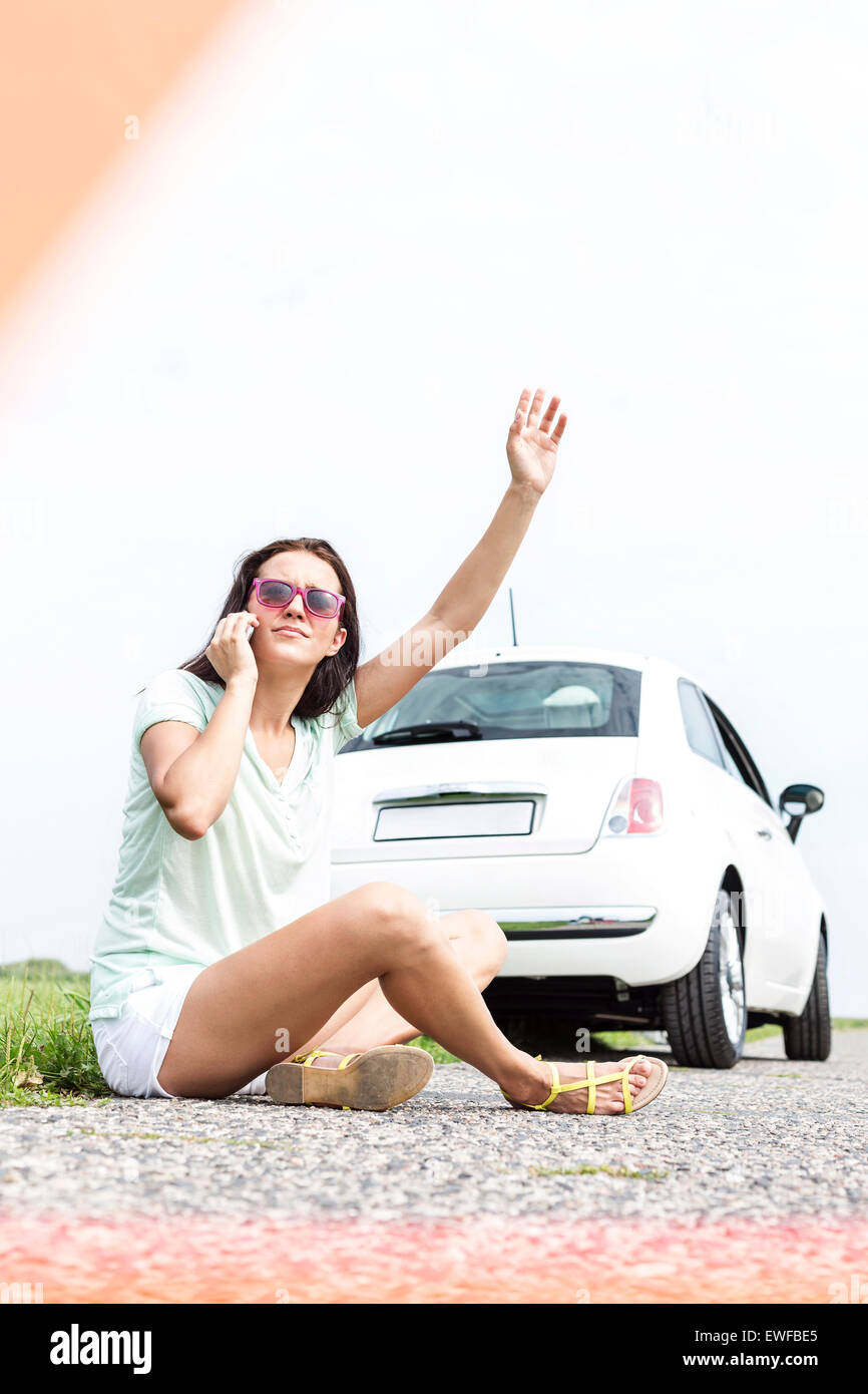 Frustrierte Frau, die bei der Verwendung von Handy kaputt Auto Trampen Stockfoto