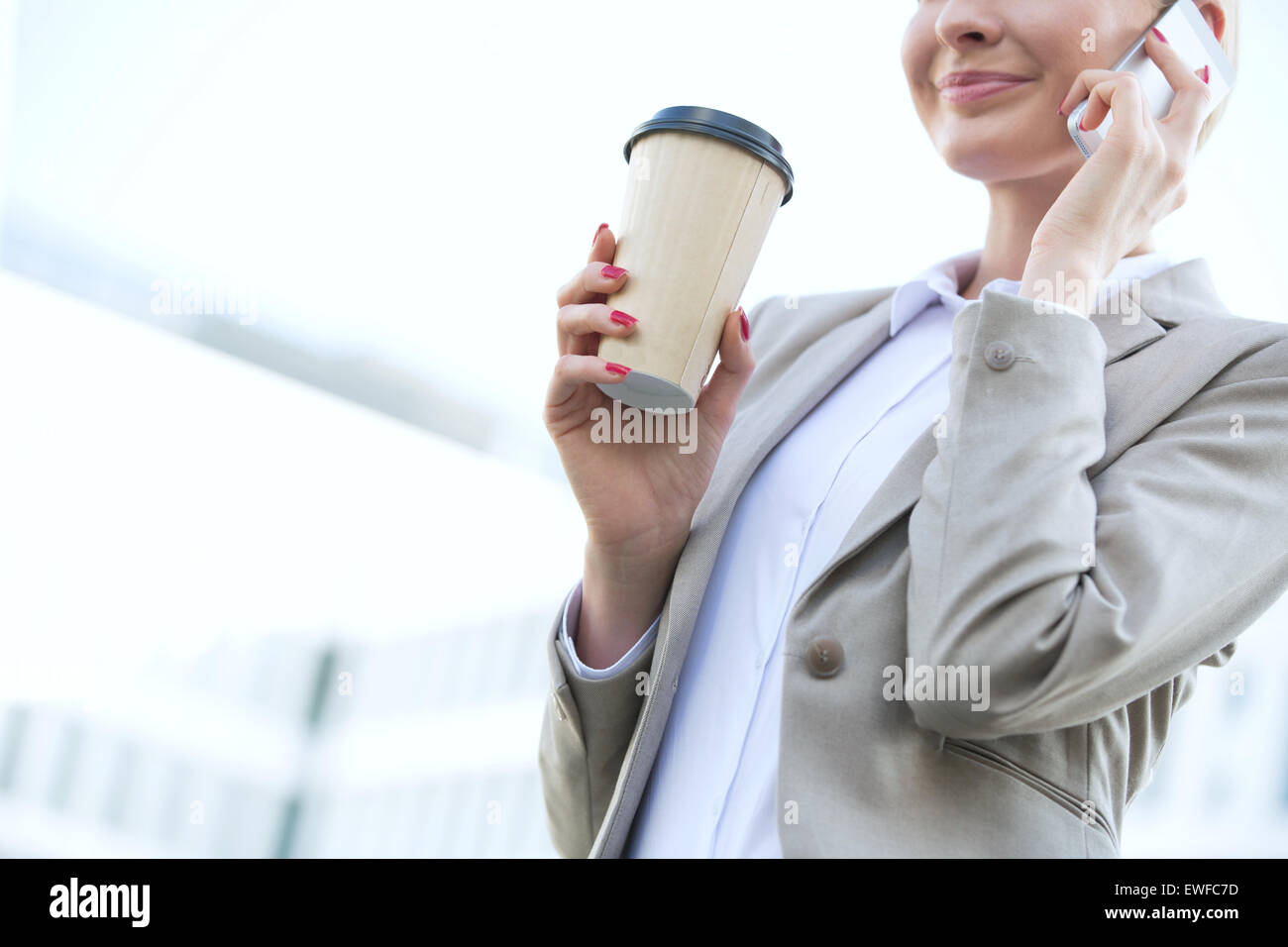 Mittelteil der Geschäftsfrau mit Handy halten Sie Einweg-Cup im freien Stockfoto