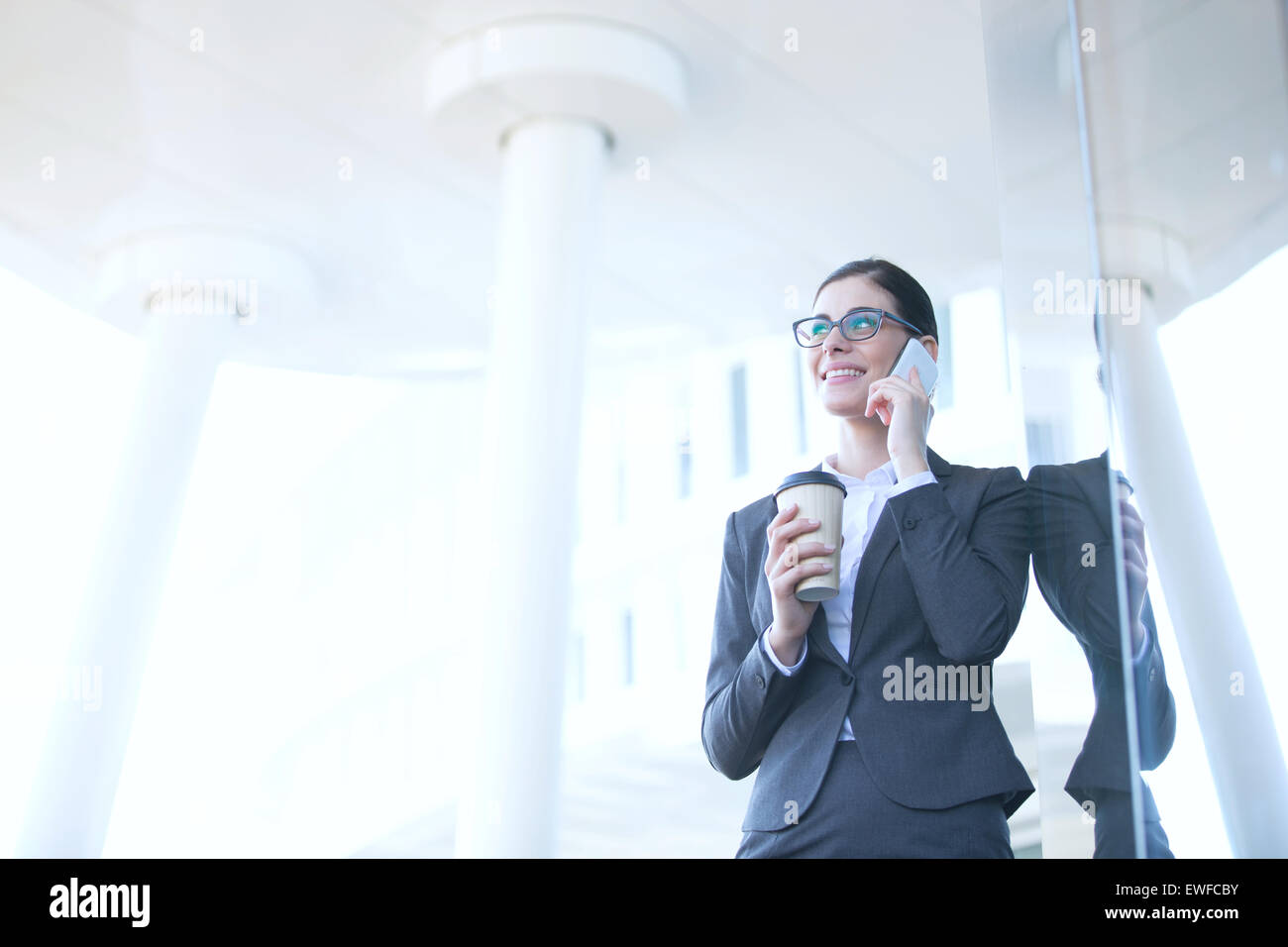 Geschäftsfrau mit Handy halten Sie Einweg-Cup im freien Stockfoto