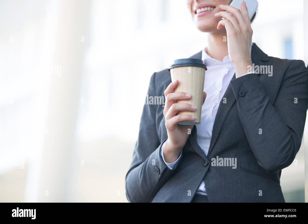 Mittelteil der Geschäftsfrau mit Handy halten Sie Einweg-Cup im freien Stockfoto
