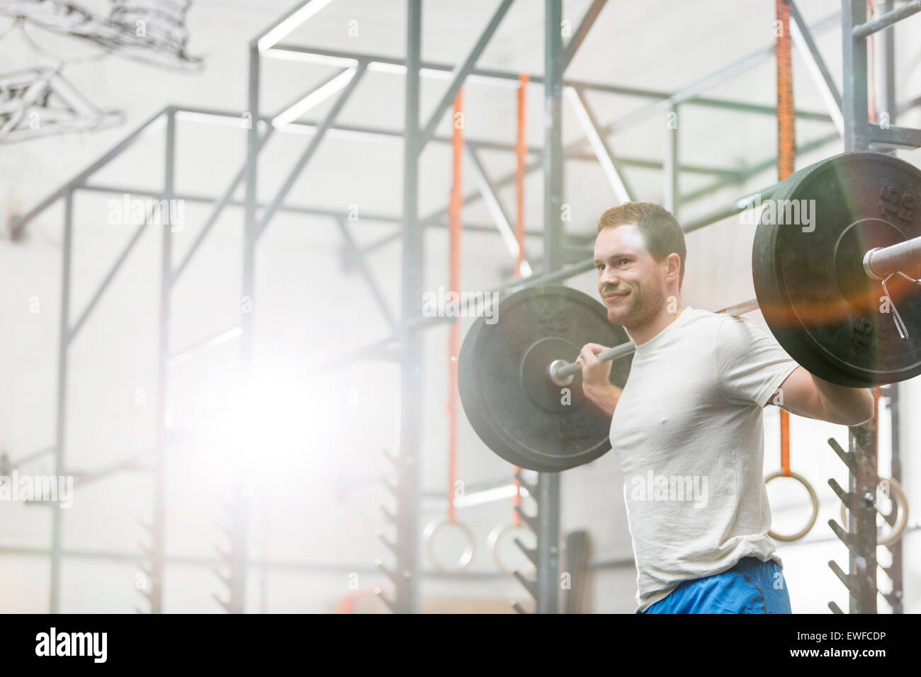 Lächelnd Mann heben Langhantel bei Crossfit gym Stockfoto