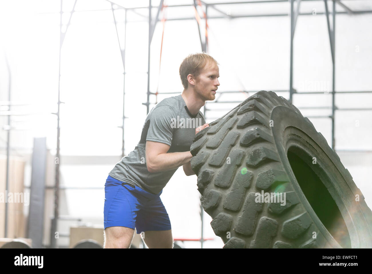 Seitenansicht des engagierten Menschen spiegeln Reifen in Crossfit gym Stockfoto