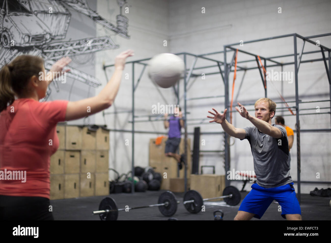 Mann wirft Medizinball in Richtung Frau in Crossfit gym Stockfoto