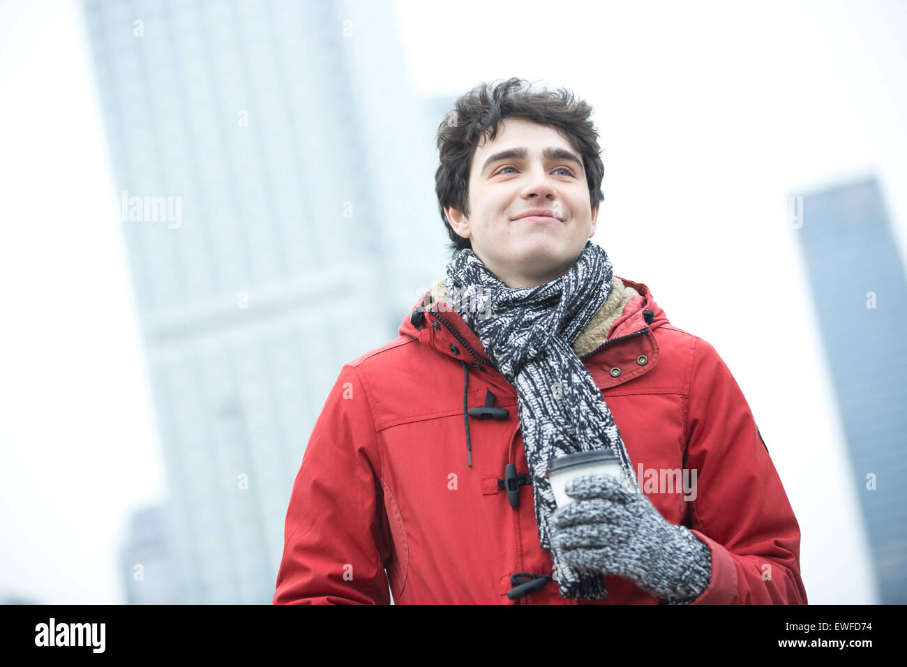 Lächelnd Mann in warme Kleidung wegsehen Einweg-Cup im Freien halten Stockfoto