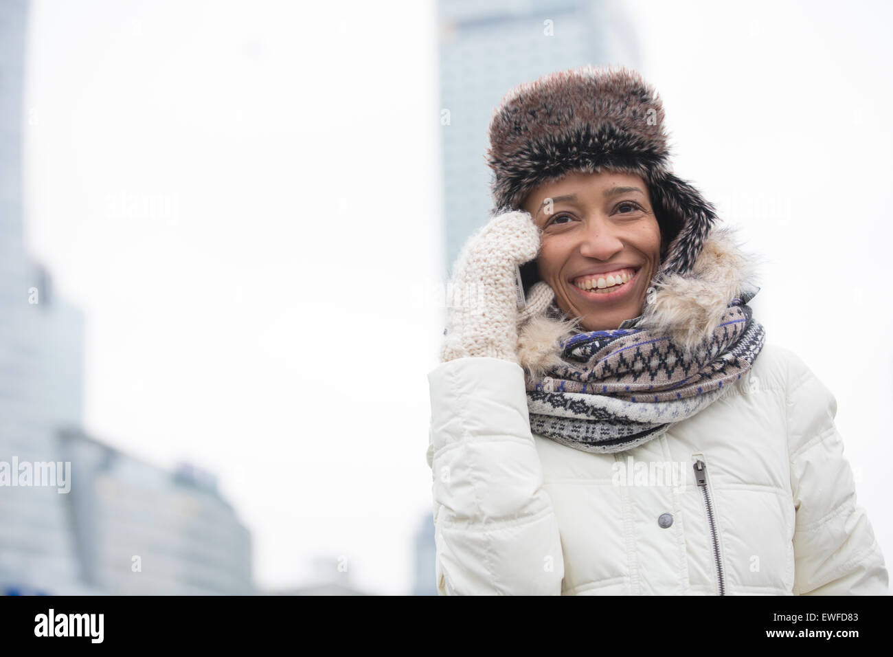 Stets gut gelaunte Frau in Winterkleidung mit Handy im freien Stockfoto
