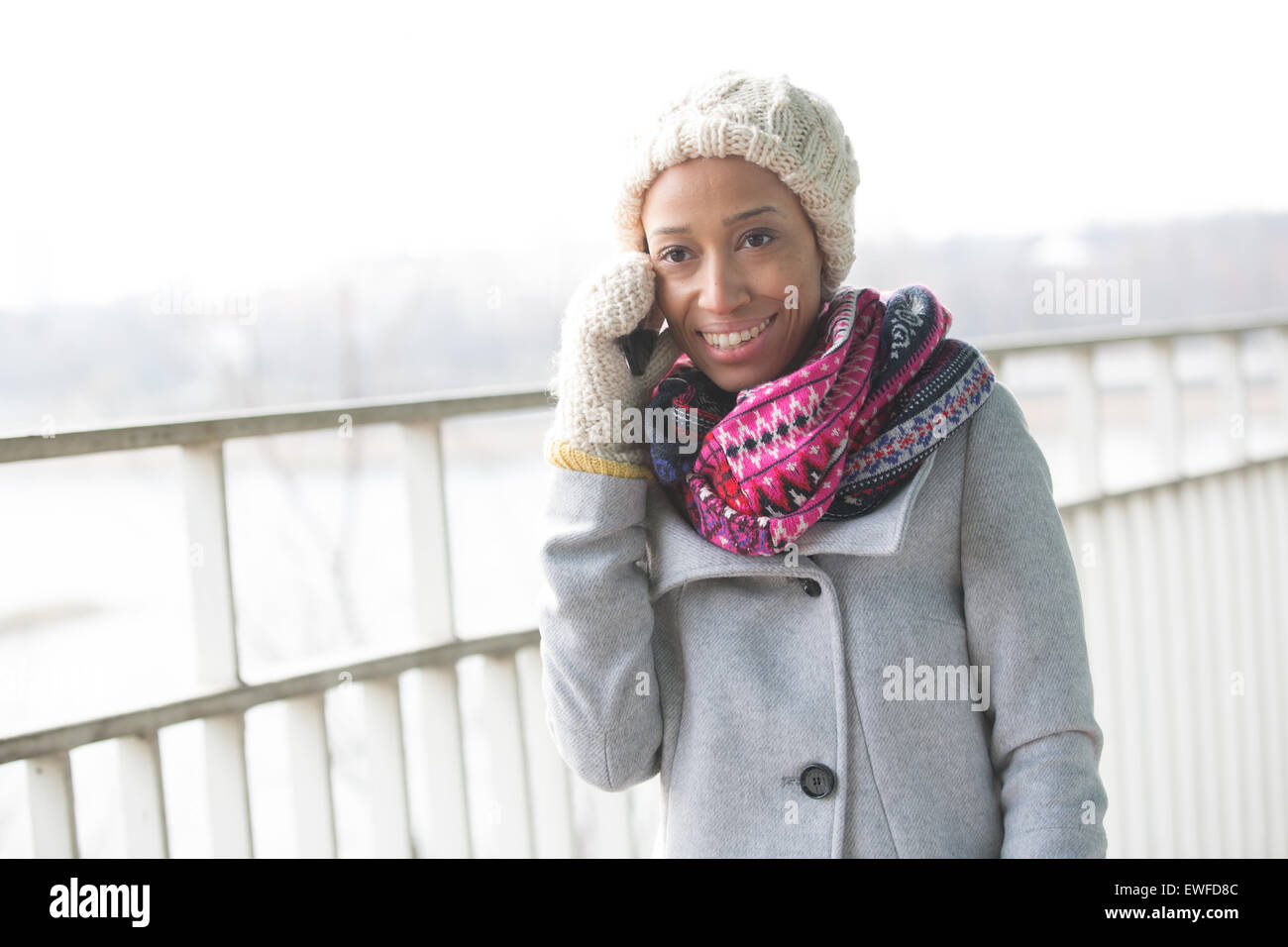 Glückliche Frau in Winterkleidung mit Handy im freien Stockfoto