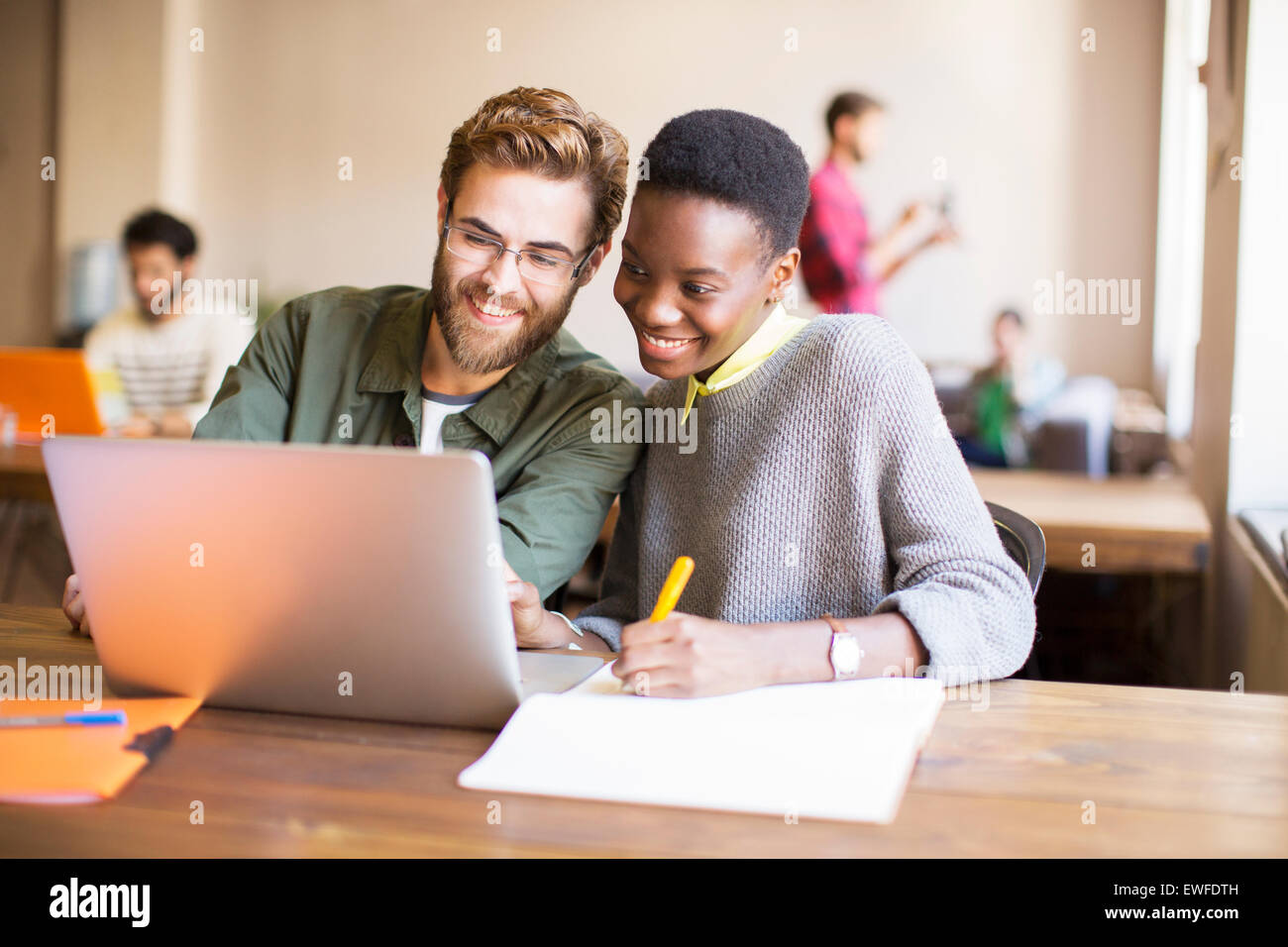 Lächelnde kreative Geschäftsleute mit Laptop und brainstorming Stockfoto