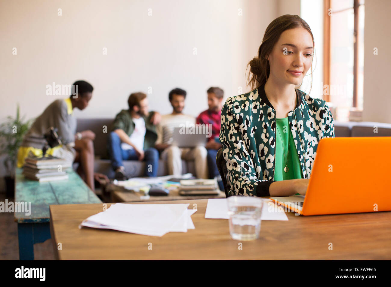 Kreative Geschäftsfrau arbeiten am Laptop mit Papierkram im Büro Stockfoto