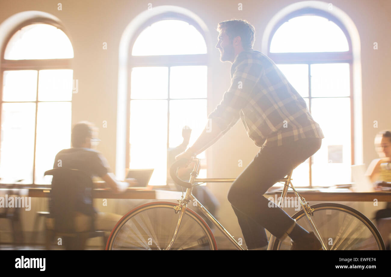 Lässige Geschäftsmann Reiten Fahrrad im sonnigen Büro Stockfoto