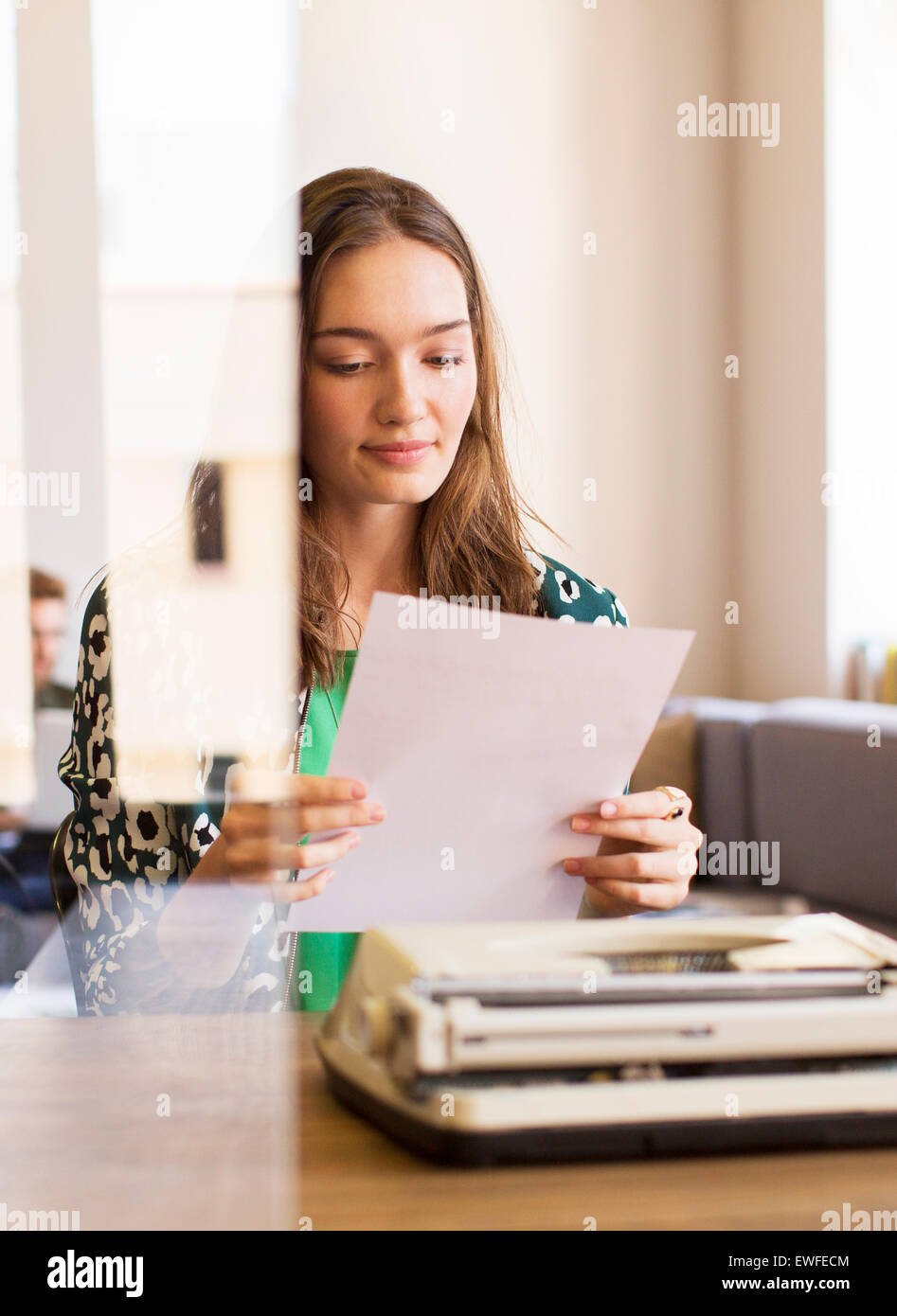 Kreative Geschäftsfrau Überprüfung Papierkram am Schreibmaschine im Büro Stockfoto